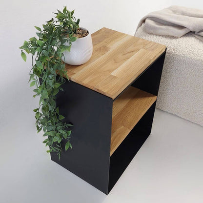 Juodas metalinis naktinis staliukas su natūralaus medžio viršumi ir lentyna šalia lovos