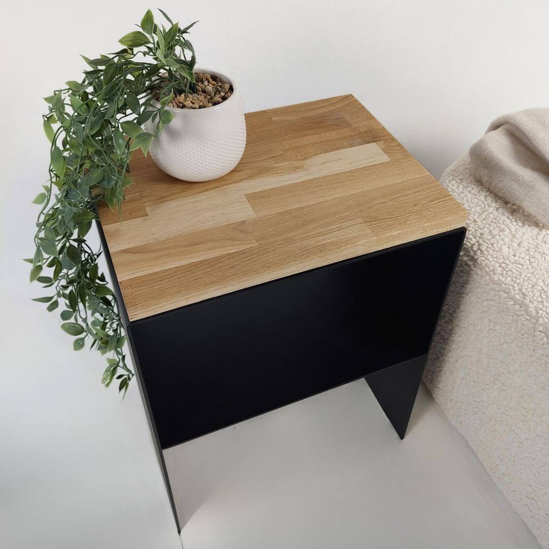 Šoninis staliukas miegamajui iš juodo metalo su mediniu viršumi interjere