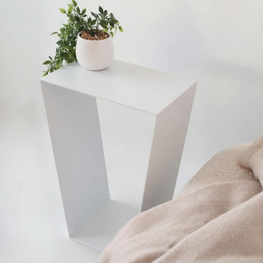 baltas staliukas prie sofos svetainėje